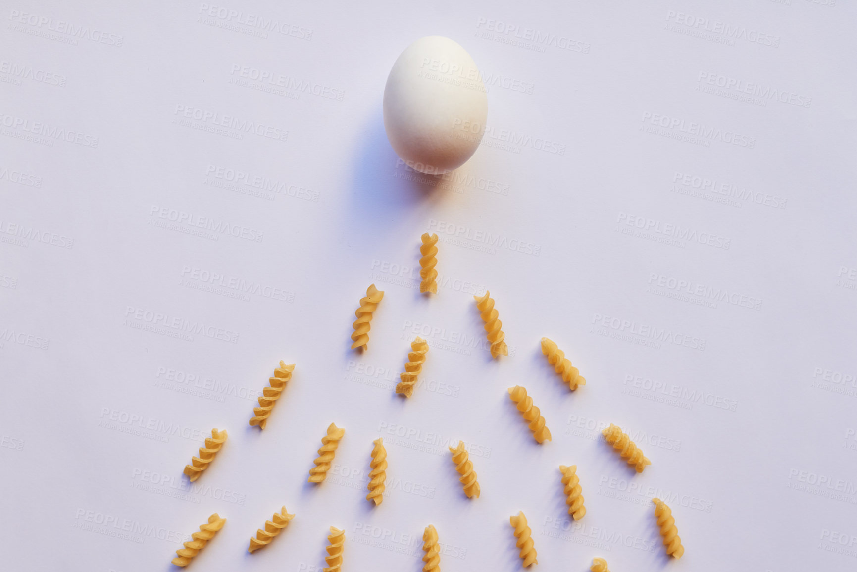 Buy stock photo Studio shot of an egg against a grey background while being surrounded by lots of little pieces of pasta