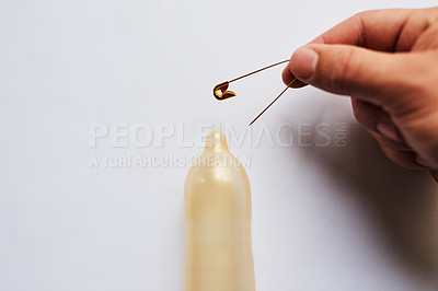 Buy stock photo Studio shot of a condom with a sharp needle on top of it placed against a grey background