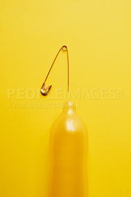 Buy stock photo Fertility, needle and risk with condom in studio for pregnancy, sexually transmitted disease or danger. Contraceptive, safety and sex education with protection on yellow background for sti prevention