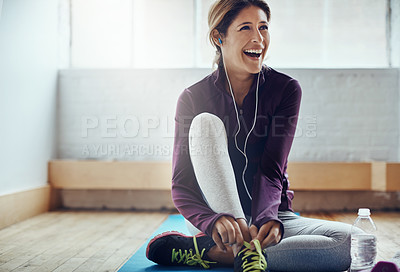 Buy stock photo Shot of an attractive young woman tying her shoelaces while working out at home