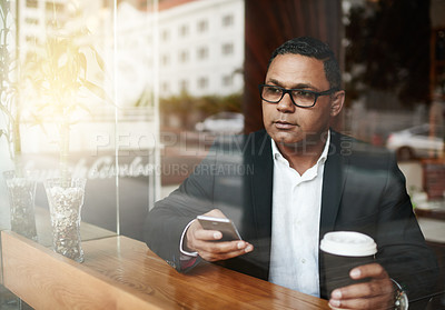 Buy stock photo High angle shot of a handsome mature businessman sending a text message while sitting in a coffee shop