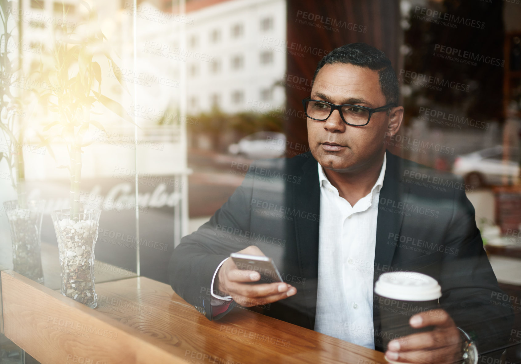 Buy stock photo High angle shot of a handsome mature businessman sending a text message while sitting in a coffee shop