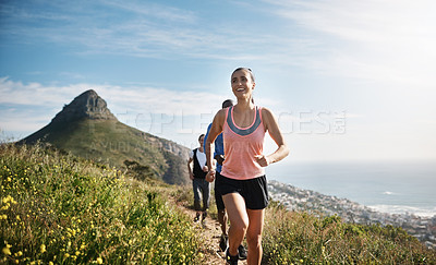 Buy stock photo Shot of a young woman exercising outside with people in the background