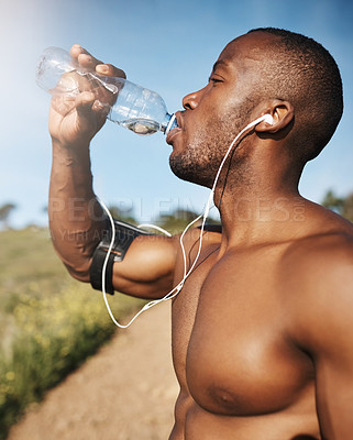 Buy stock photo Cropped shot of a young man drinking a bottle of water while out exercising
