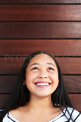 Buy stock photo Girl, thinking and smile by wood background for daydream with happiness, childhood and youth. Child, thoughtful and smiling for curious by wooden wall outdoor with looking up, positivity and growth