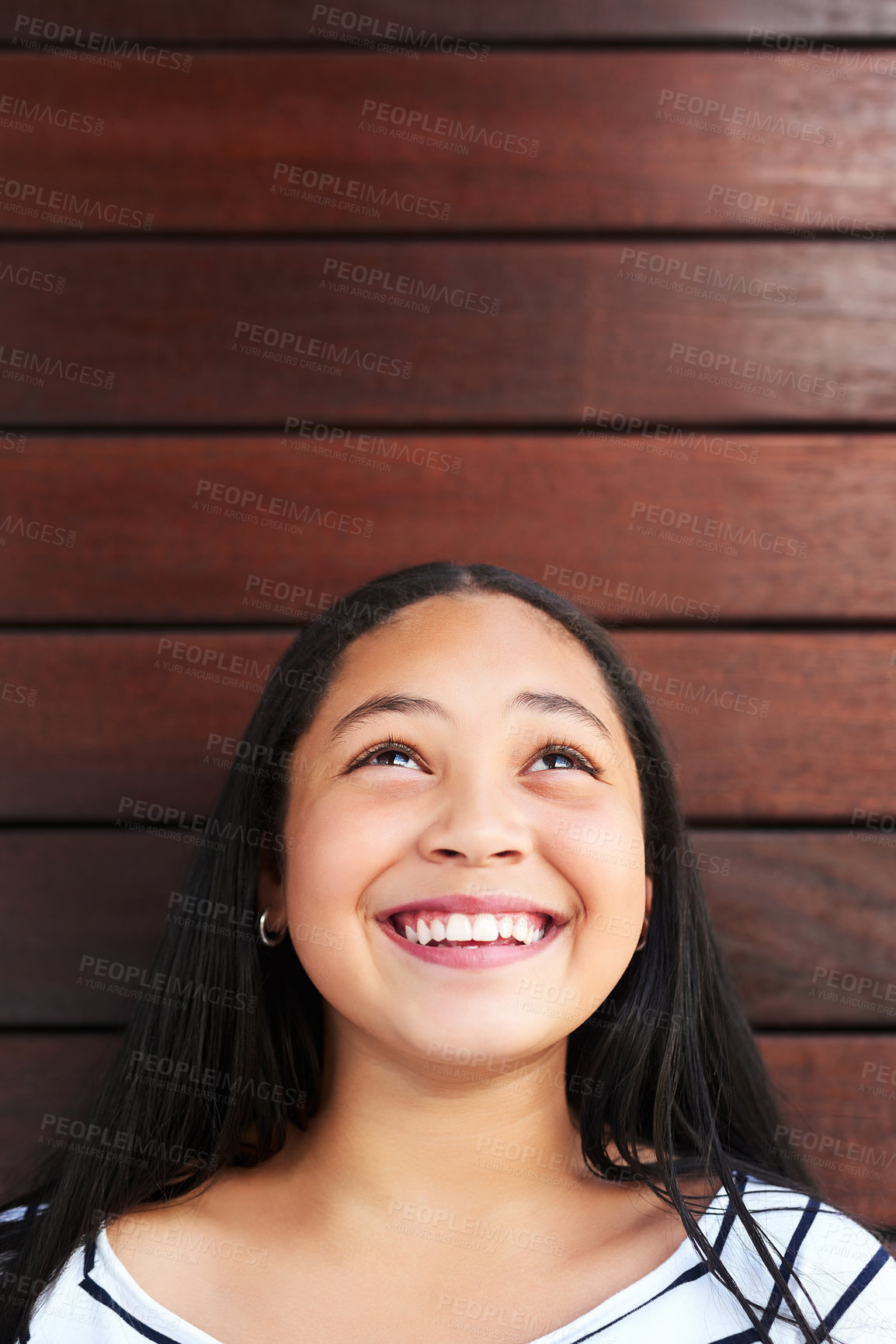 Buy stock photo Girl, thinking and smile by wood background for daydream with happiness, childhood and youth. Child, thoughtful and smiling for curious by wooden wall outdoor with looking up, positivity and growth