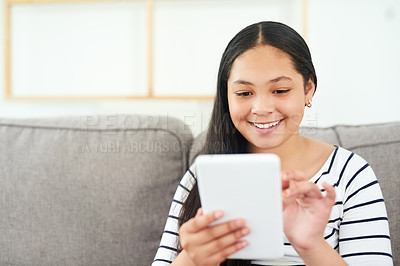 Buy stock photo Shot of a happy young girl relaxing on the sofa and using a digital tablet
