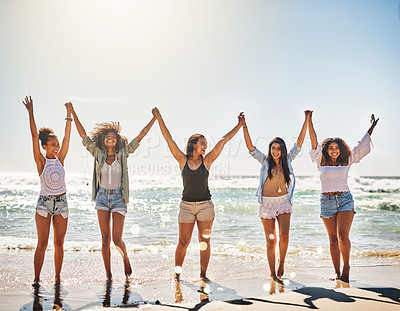 Buy stock photo Shot of a group of cheerful friends holding hands on the beach