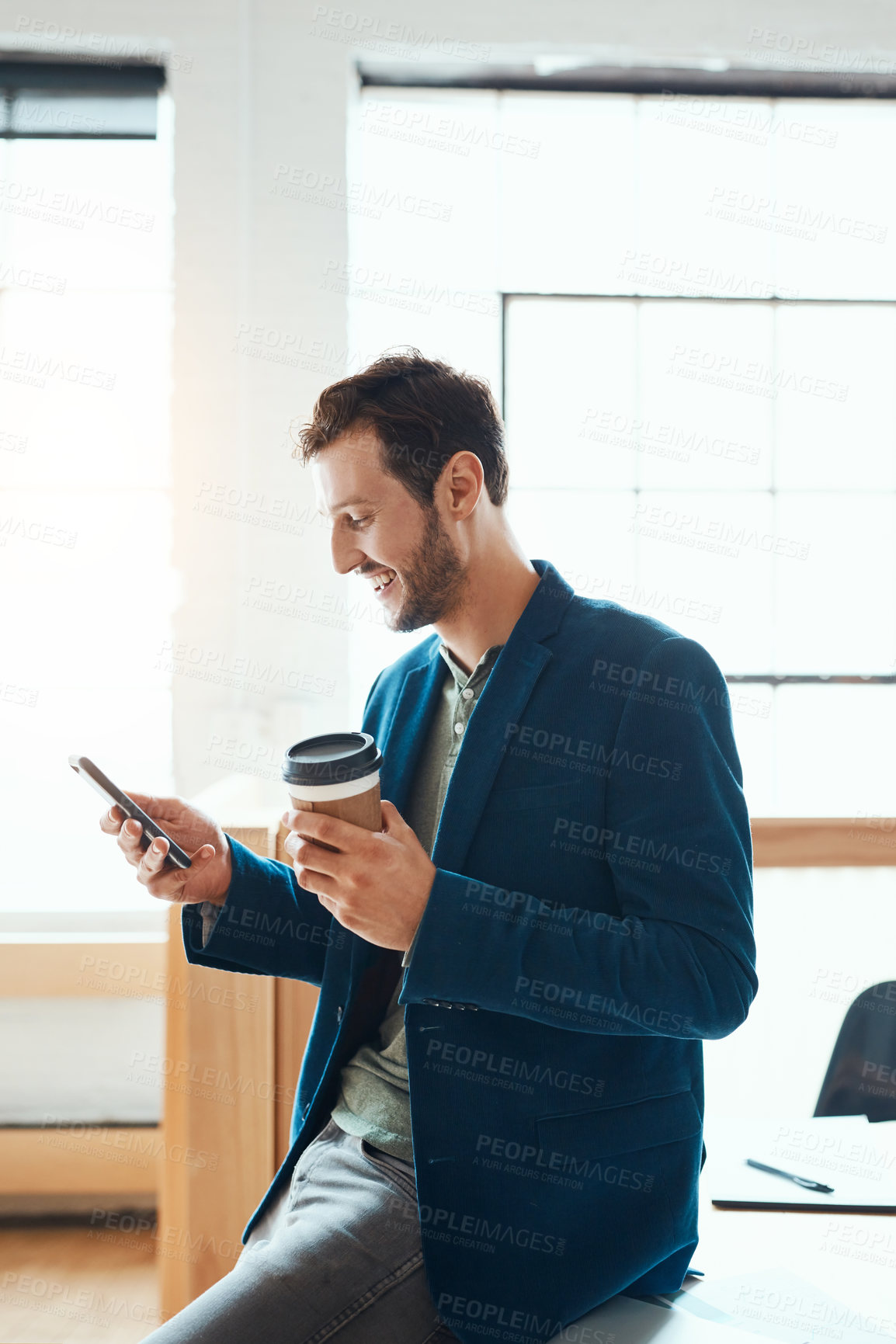 Buy stock photo Cropped shot of a handsome young businessman using his cellphone while working in a modern office