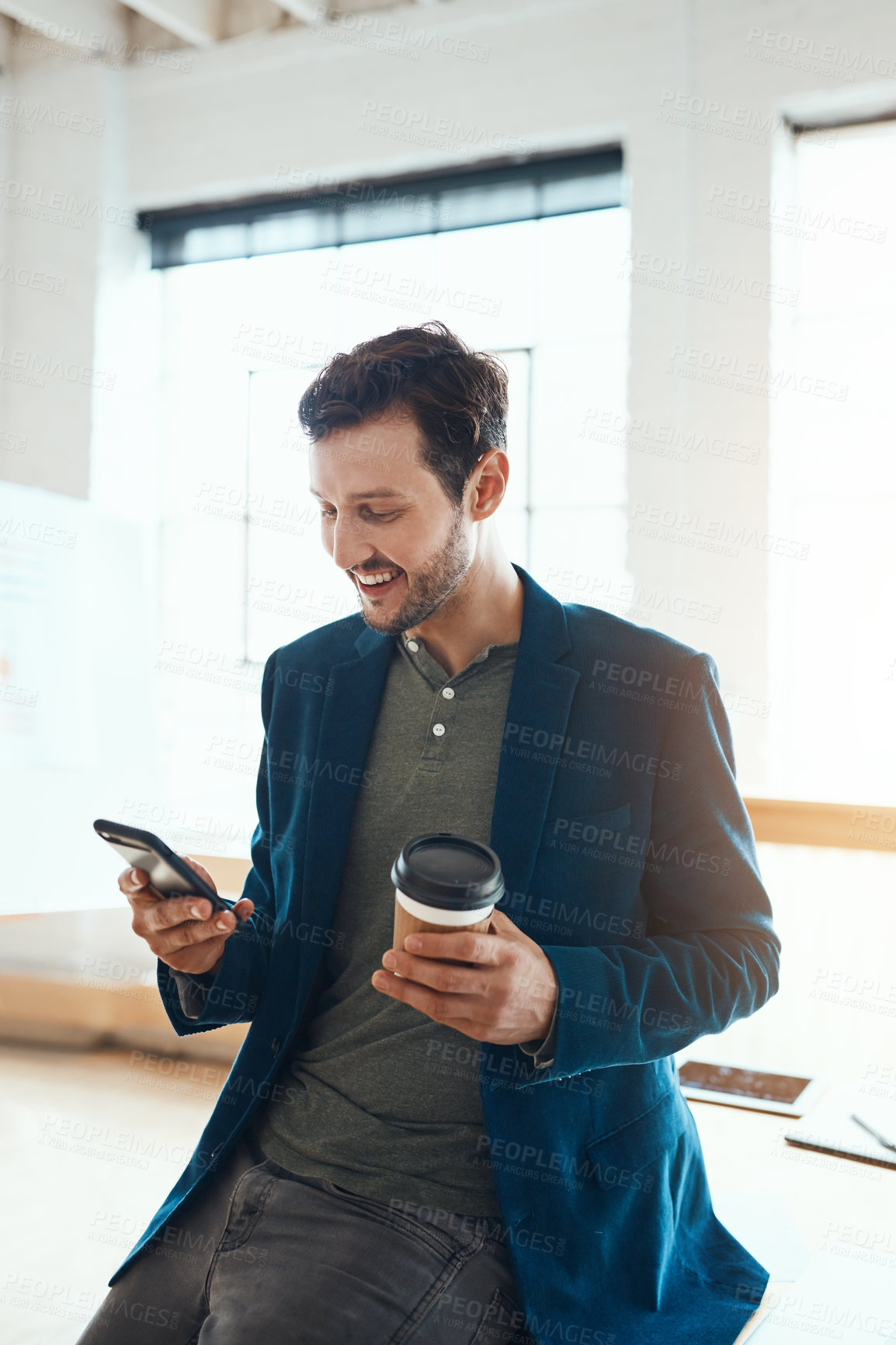 Buy stock photo Cropped shot of a handsome young businessman using his cellphone while working in a modern office