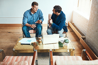 Buy stock photo Shot of two young businessmen having a discussion and using a laptop together in a modern office