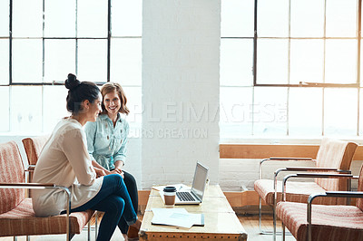 Buy stock photo Shot of two young businesswomen discussing paperwork in a modern office