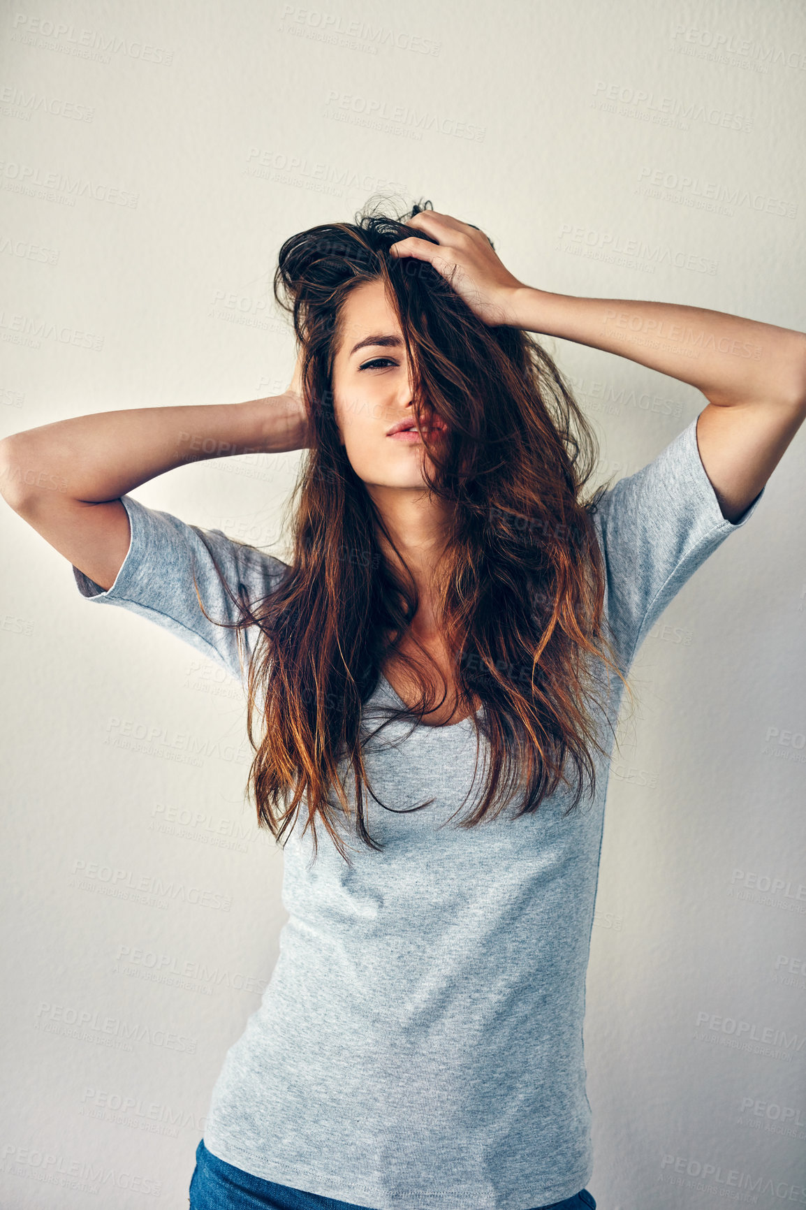 Buy stock photo Studio shot of an attractive young woman posing with her hands in her hair