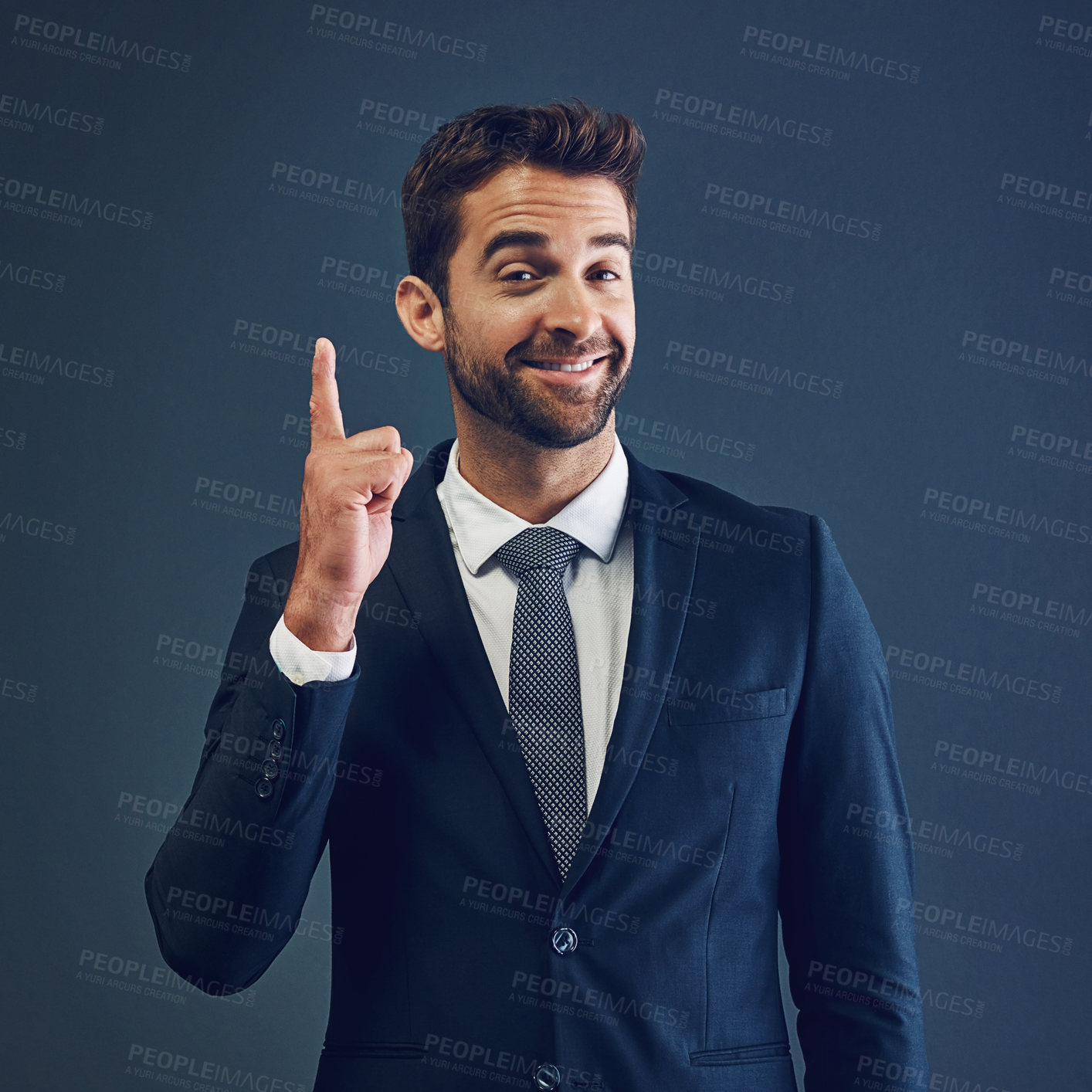 Buy stock photo Studio portrait of a handsome young businessman pointing against a dark background