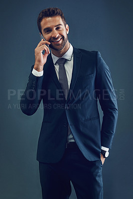 Buy stock photo Studio shot of a handsome young businessman talking on a cellphone against a dark background
