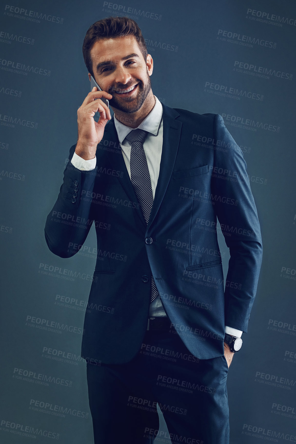 Buy stock photo Studio shot of a handsome young businessman talking on a cellphone against a dark background