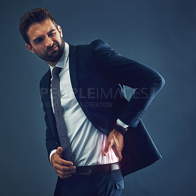 Buy stock photo Studio shot of a handsome young businessman suffering with back pain against a dark background