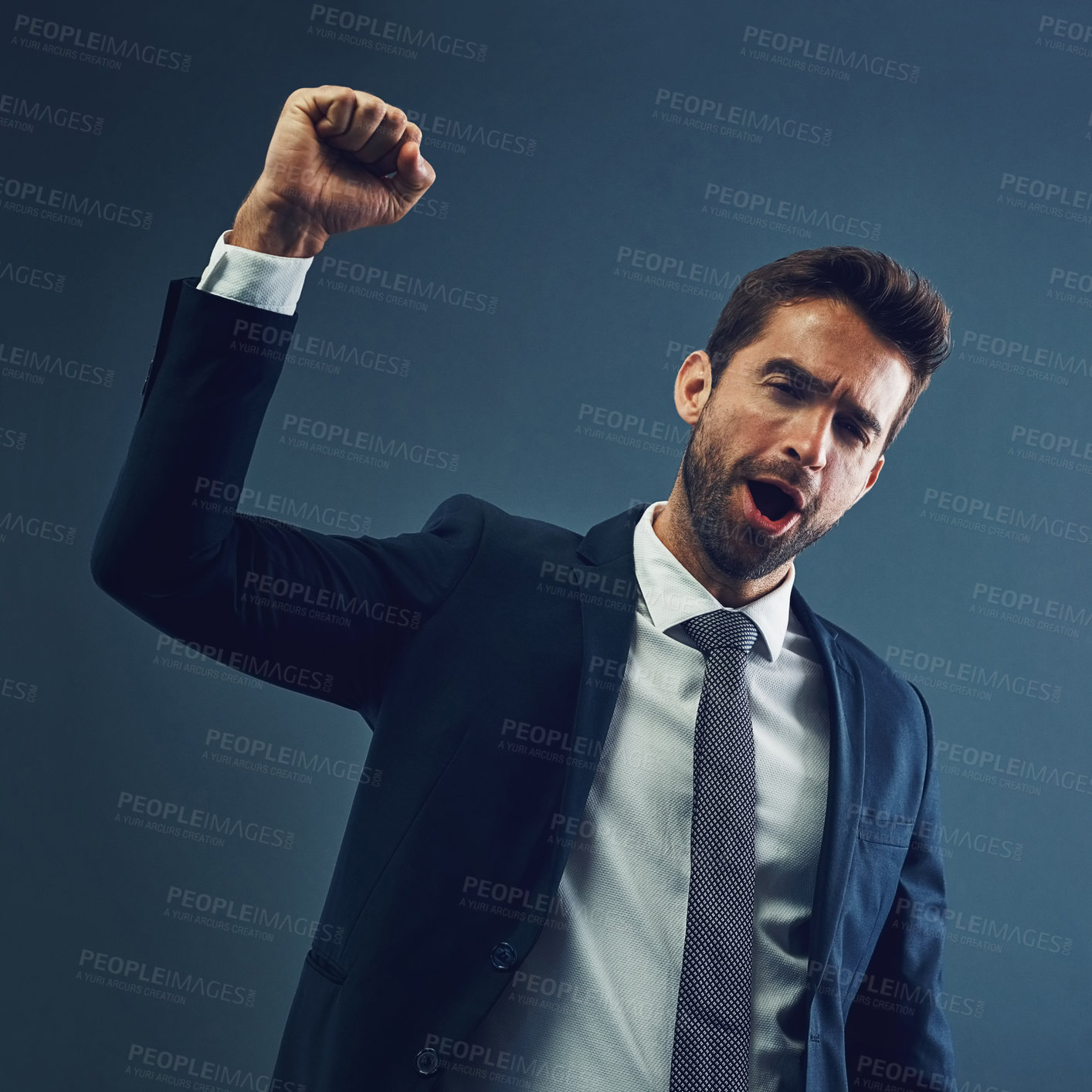 Buy stock photo Studio portrait of a handsome young businessman cheering against a dark background