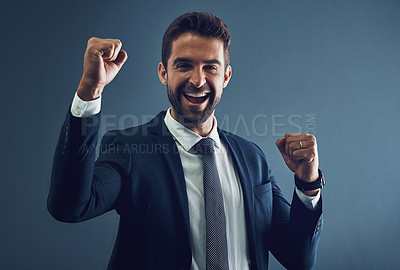 Buy stock photo Studio portrait of a handsome young businessman cheering against a dark background