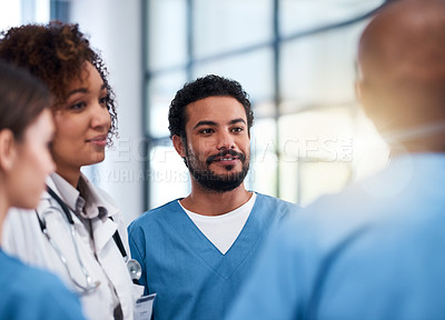 Buy stock photo Shot of a cheerful group of doctors having a discussion while standing inside of a hospital during the day