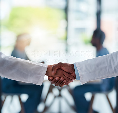 Buy stock photo Shot of two unrecognizable doctors shaking hands inside of a hospital during the day