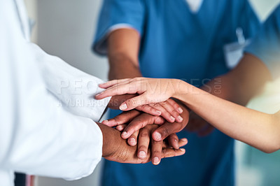 Buy stock photo Shot of a group of unrecognizable doctors forming a huddle with their hands inside of a hospital during the day