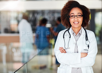 Buy stock photo Portrait of a cheerful young doctor standing with his arms folded inside of a hospital during the day