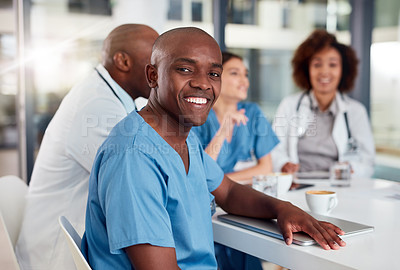 Buy stock photo Portrait of a cheerful young doctor seated at a table during a meeting inside of a hospital during the day
