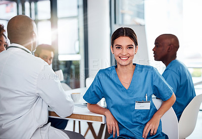 Buy stock photo Portrait of a cheerful young doctor seated at a table during a meeting inside of a hospital during the day