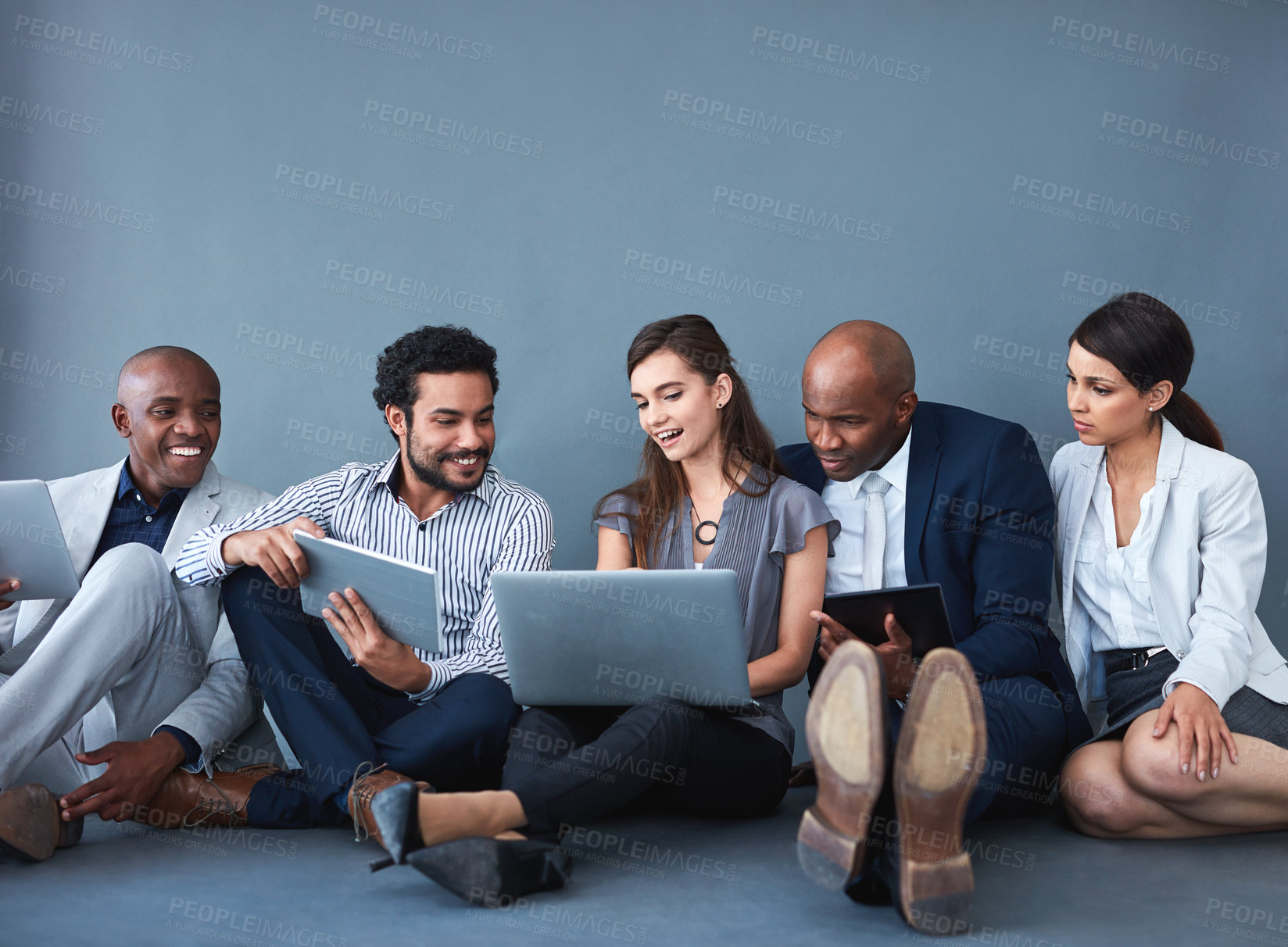 Buy stock photo Studio shot of a group of corporate businesspeople using different devices against a gray background