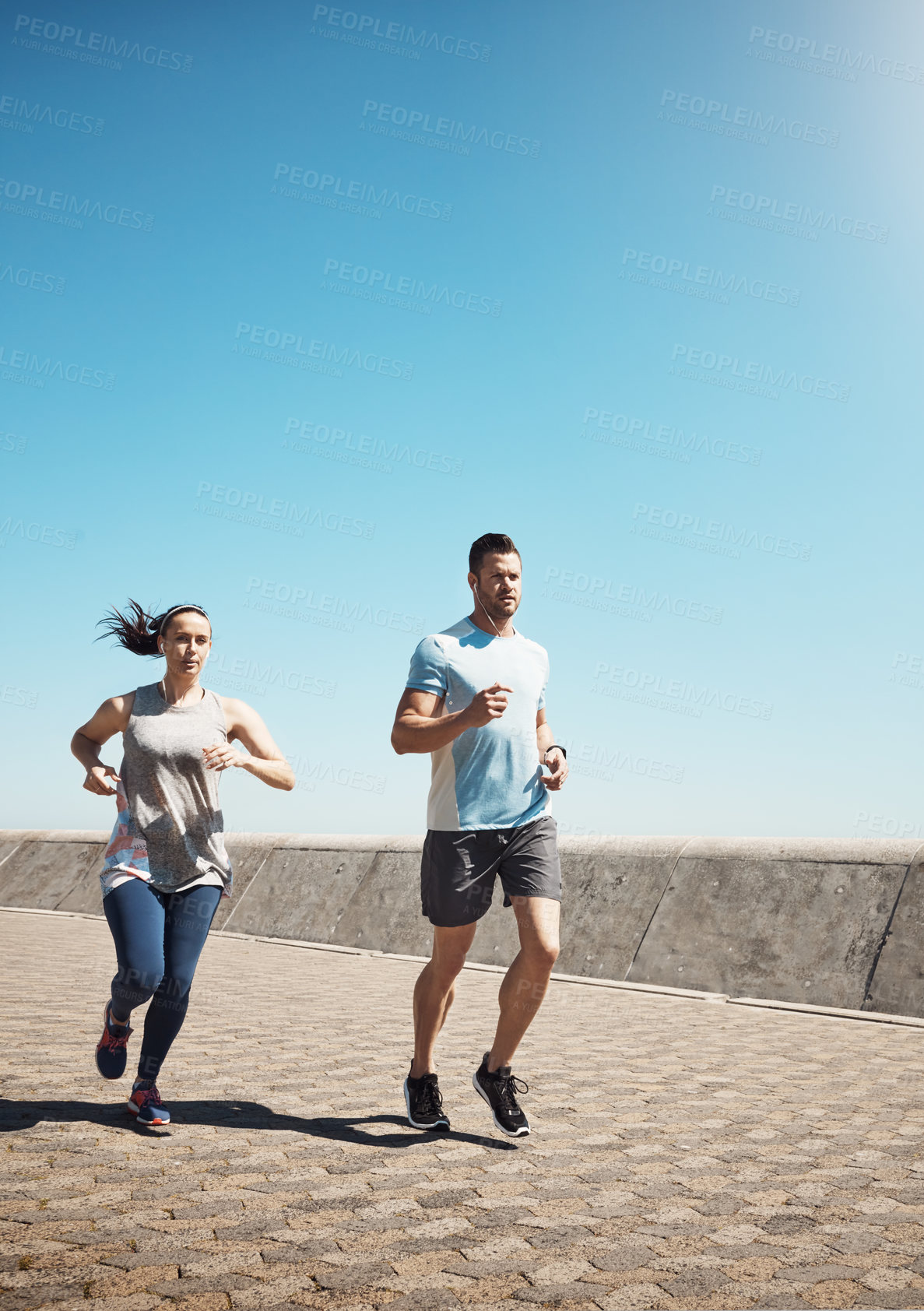 Buy stock photo Full length shot of a young couple out for a run on the promenade