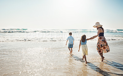 Buy stock photo Rear view shot of a mother bonding with her two little children at the beach