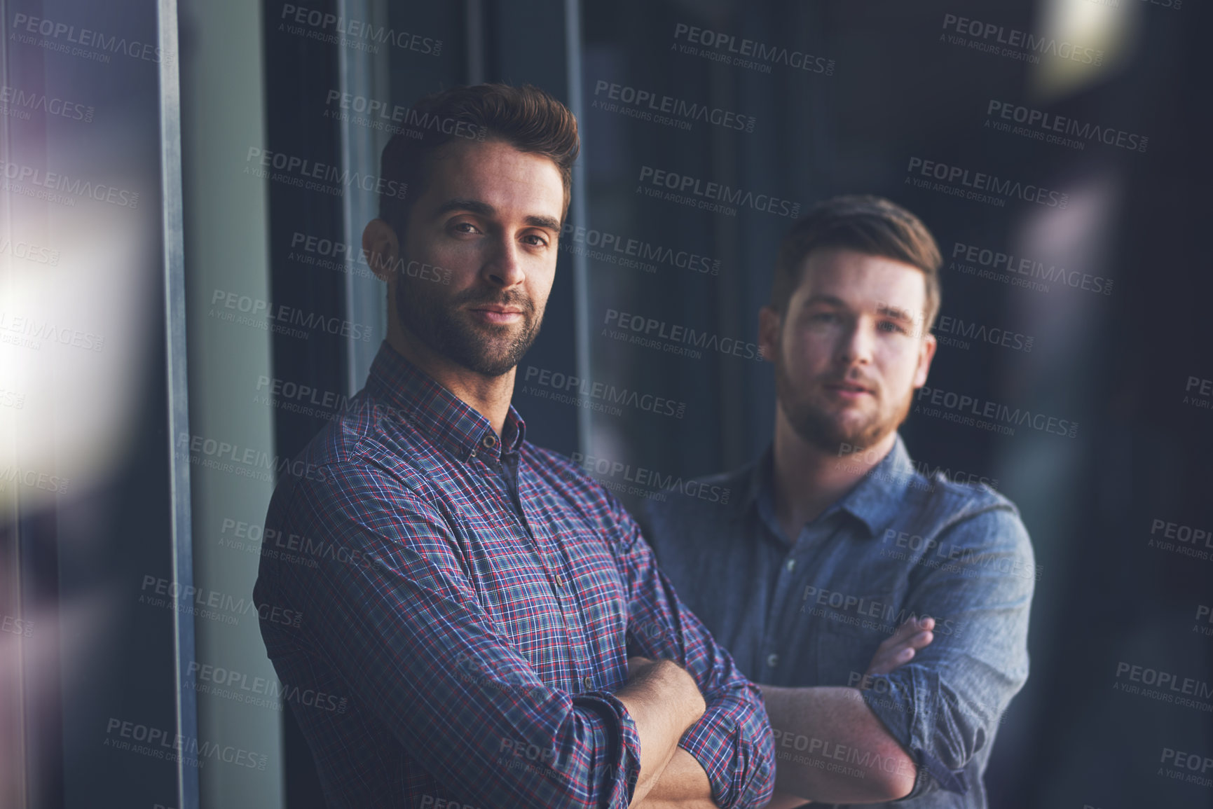 Buy stock photo Portrait of two confident young businessmen standing with their arms crossed