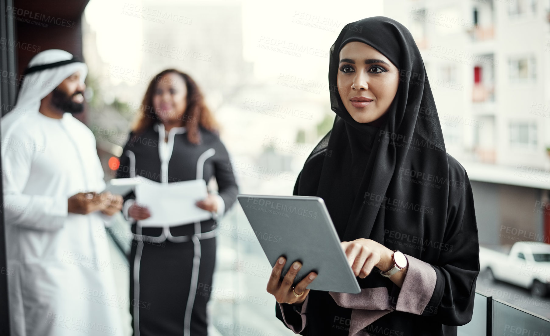 Buy stock photo Cropped shot of an attractive young businesswoman dressed in Islamic traditional clothing using a tablet on her office balcony