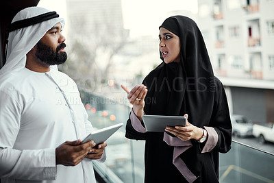 Buy stock photo Cropped shot of two young businesspeople dressed in Islamic traditional clothing using their tablets on the office balcony