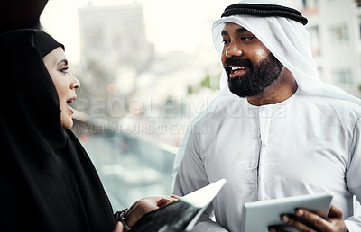 Buy stock photo Cropped shot of two young businesspeople dressed in Islamic traditional clothing using their tablets on the office balcony