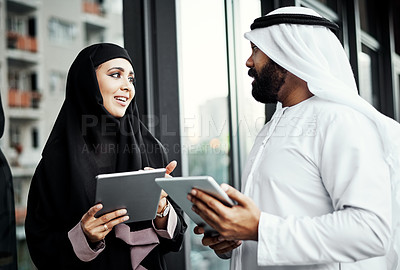 Buy stock photo Cropped shot of two young businesspeople dressed in Islamic traditional clothing using their tablets on the office balcony