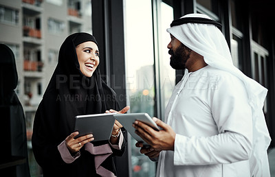 Buy stock photo Cropped shot of two young businesspeople dressed in Islamic traditional clothing using their tablets on the office balcony