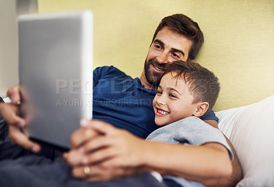 Buy stock photo Shot of a young man using a digital tablet with his son at home