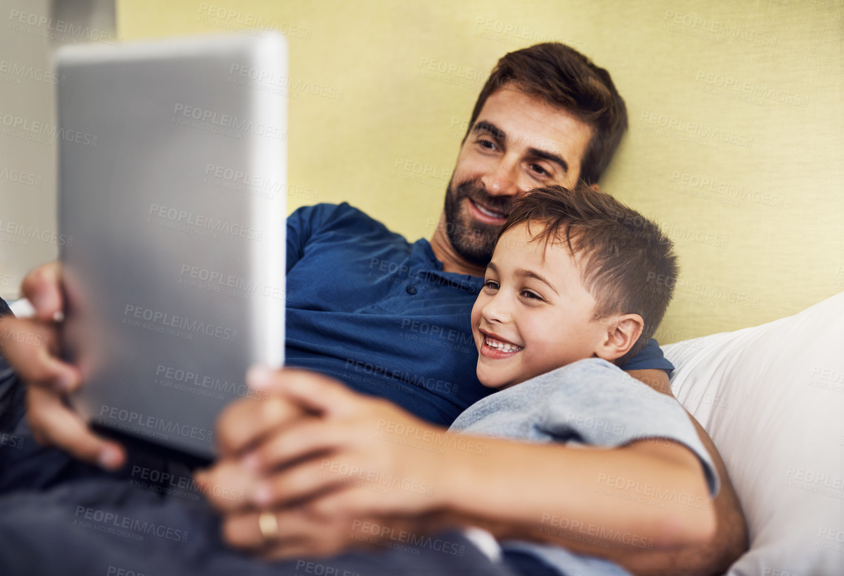 Buy stock photo Shot of a young man using a digital tablet with his son at home