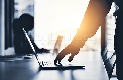 Buy stock photo Silhouetted shot of an unrecognizable businessman using a laptop in an office