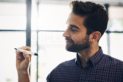Buy stock photo Shot of a confident young businessmen writing on a board with a pen inside of the office