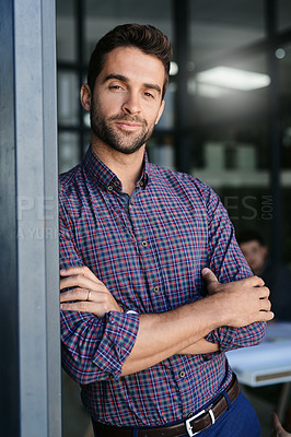 Buy stock photo Portrait of a confident young businessman standing with his arms folded inside of the office during the day
