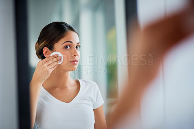 Buy stock photo Shot of an attractive young woman cleaning her face with cotton wool in the bathroom
