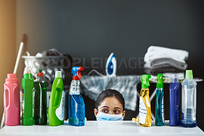 Buy stock photo Shot of a young woman wearing a mask and cleaning a table at home