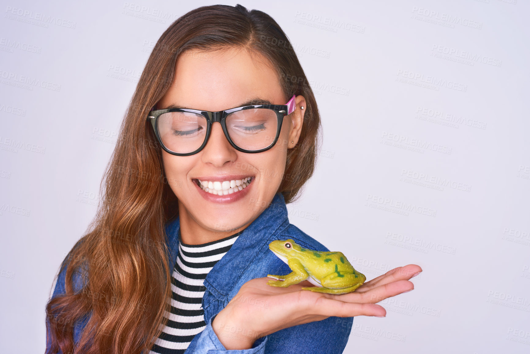 Buy stock photo Happy, woman and fashion frog in studio for fairytale transformation, hope and romance fantasy with magic. Female, person, smile and reptile with brand glasses, explore and wish on purple background