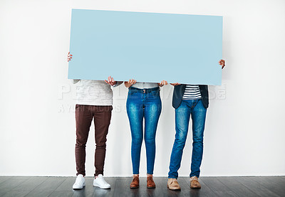 Buy stock photo Studio shot of a group of people covering themselves with a blank placard against a white background