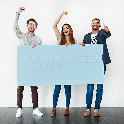 Buy stock photo Studio shot of a diverse group of young people holding a blank placard and cheering against a white background