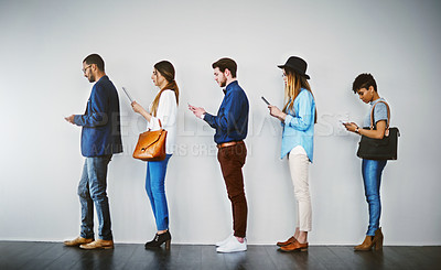 Buy stock photo Shot of a group of businesspeople using wireless technology while waiting in line