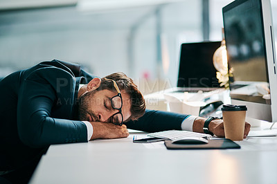 Buy stock photo Shot of a tired young businessman sleeping on his desk inside of the office during the day